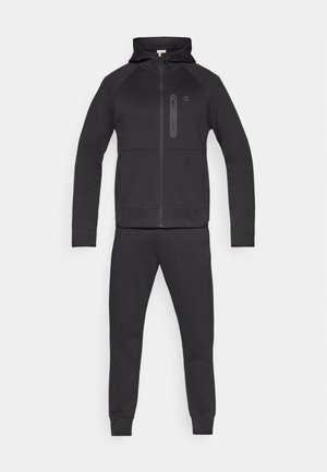 Trening sportiv negru din material moale, cu glugă cu fermoar și buzunar frontal, și pantaloni conici cu manșete la glezne.