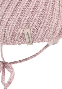 Close-up of pink and white ribbed knit hat with tied straps and a beige label.