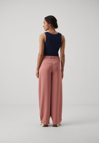 Námornícky tank top v kombinácii s svetloružovými širokými nohavicami. Nohavice majú upravený pás a dve zadné vrecká. Hladká textúra látky.
