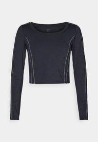 Schwarzes Langarm-Crop-Top aus elastischem Material, mit kontrastierenden weißen Steppnähten entlang der Nähte und einem runden Halsausschnitt.