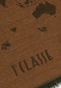 Tessuto marrone con motivo a mappa con continenti più scuri, che mostra il testo "T'CLASSE" in un font audace e scuro lungo il bordo inferiore.