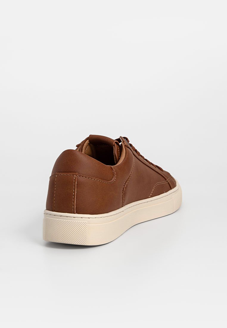 Baskets en cuir marron avec une texture lisse, de forme arrondie et une semelle en caoutchouc couleur crème. Présente des coutures subtiles et des détails de laçage.