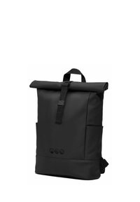 Schwarzer Rolltop-Rucksack mit vorderem Schnallenriemen, Seitentaschen und drei kleinen kreisförmigen Symbolen nahe der unteren Mitte.