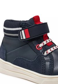 Le sneakers alte blu marine presentano una finitura in pelle testurizzata, un colletto a maglia a righe, dettagli rossi e una fascia elastica, con lacci bianchi a contrasto.
