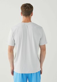 Szary, sportowy T-shirt z krótkim rękawem, okrągłym dekoltem, teksturowanym materiałem i subtelnym wzorem. Brak widocznych logo lub nadruków.