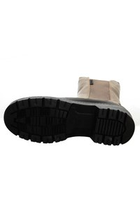 Tan boot with a smooth leather upper and elastic side panel; rubber sole with deep grooves for traction and flexibility.