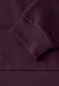 Tejido de sudadera de color púrpura oscuro con puños y dobladillo acanalados. Textura suave con un acabado liso. Costuras reforzadas a lo largo de los bordes para mayor durabilidad.