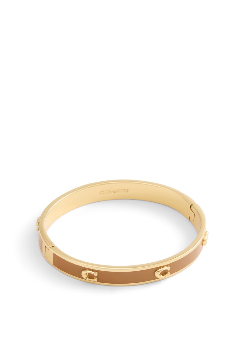 Gold-tone metal bangle bracelet with a smooth, tan enamel stripe and embossed accents. Features a hinge opening for easy wear.