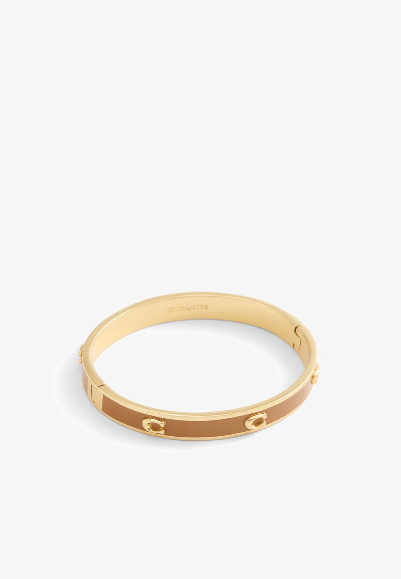 Gold-tone metal bangle bracelet with a smooth, tan enamel stripe and embossed accents. Features a hinge opening for easy wear.