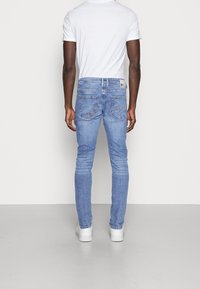 Jeans de mezclilla azul claro con corte slim, que cuentan con cinco bolsillos, una cinturilla con trabillas y una etiqueta en la parte trasera.