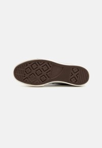 Rubberen sneakerzool met een gestructureerd bruin patroon, bestaande uit diamanten en horizontale lijnen; witte buitenrand. Duidelijk gripontwerp verbetert de tractie.