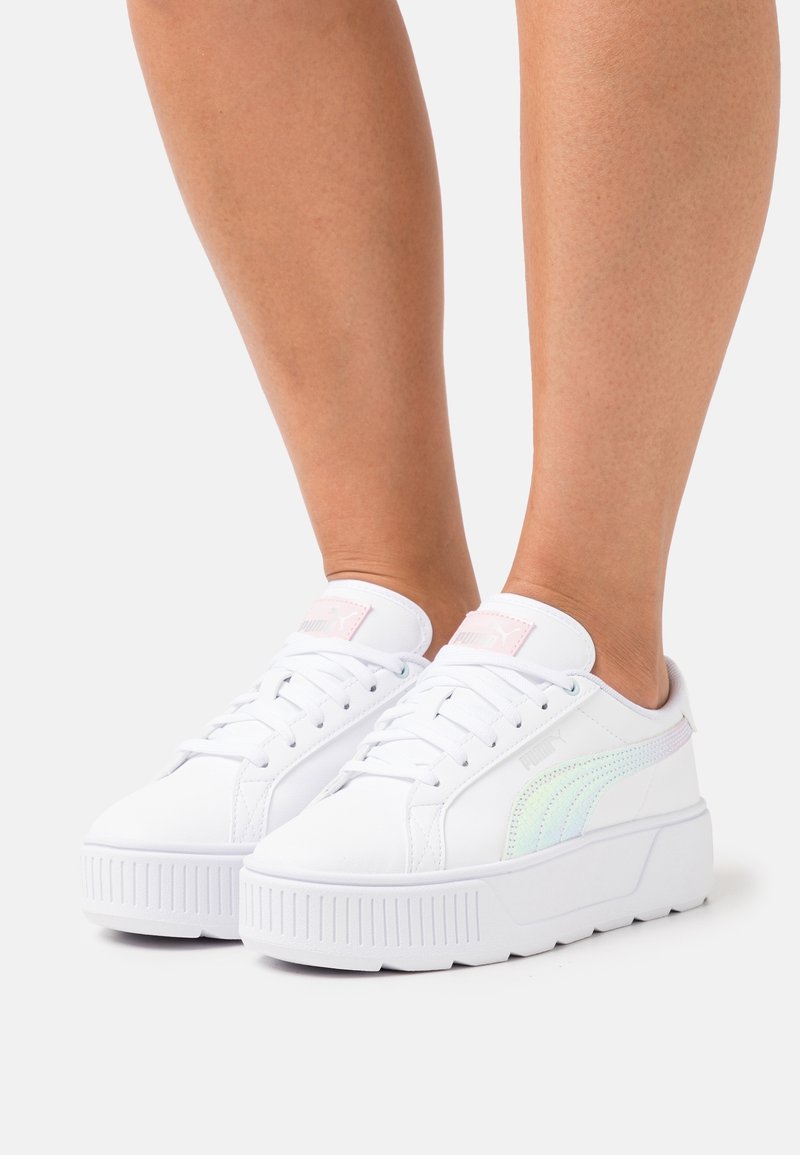 Białe trampki na platformie o gładkim skórzanym wykończeniu, z pastelowym, iryzującym paskiem i różowym akcentem na języku.