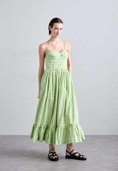 Groene en witte gingham jurk met een aansluitende lijfje, spaghetti-bandjes en een vloeiende rok met een gerimpelde zoom. Draag het met zwarte sandaaltjes met bandjes.
