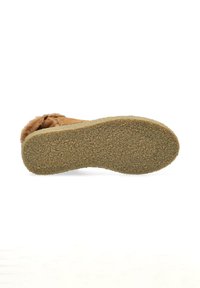 Suela de zueco de ante marrón con un agarre de goma texturizado. Forro interior de piel suave visible a lo largo de los bordes, proporcionando comodidad y calidez.