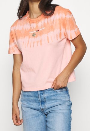 Camiseta de manga corta de color rosa con un patrón de tie-dye en naranja, que presenta un logo blanco de "TOMMY JEANS" en el pecho y un corte relajado.