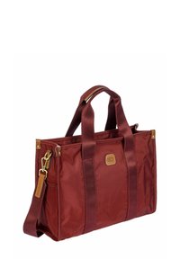 Sac fourre-tout rectangulaire bordeaux avec double poignées, bandoulière amovible, quincaillerie dorée et petit patch en cuir de marque à l'avant.