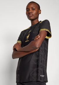 Svart atletisk jersey med preget mønster, gulldetaljer og teksten "MEXICO". Designet for pusteevne med "HEAT.RDY"-detalj.