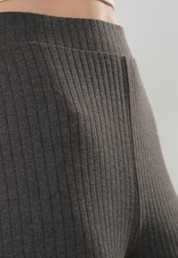 Mörkgrå ribbade leggings med hög midja, mjuk textur, vertikala linjer och en åtsittande design.