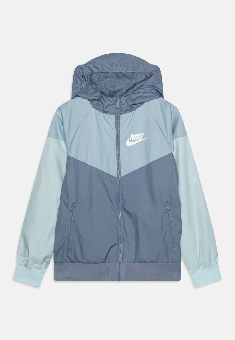 Nike-huppari sinisen eri sävyissä, jossa on vetoketjullinen etuosa, kontrastiväriset hihat, logo rinnassa ja joustavat hihansuut tiukkaa istuvuutta varten.