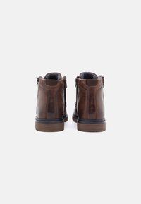 Boots de glezna din piele maro cu o textură netedă, fermoare laterale și talpă din cauciuc. Vedere din spate care arată tocul întărit și cusătura contrastantă.