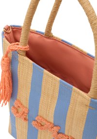 Vävd halmbag med blå och beige ränder, som visar ett mjukt persikointeriör, tvinnade håndtag och dekorativt tofsdetalj.