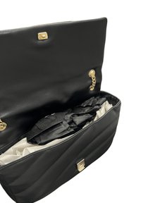 Borsa a mano in pelle nera con design trapuntato, dettagli in oro, catena e interno in tessuto. Contiene accessori neri all'interno.