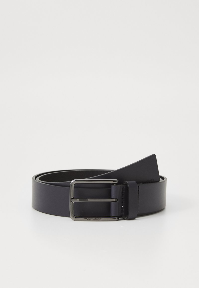 Sort læderbælte med en sølvmetalspænde, der har en glat tekstur og et klassisk design. Enderne taper til en spids.