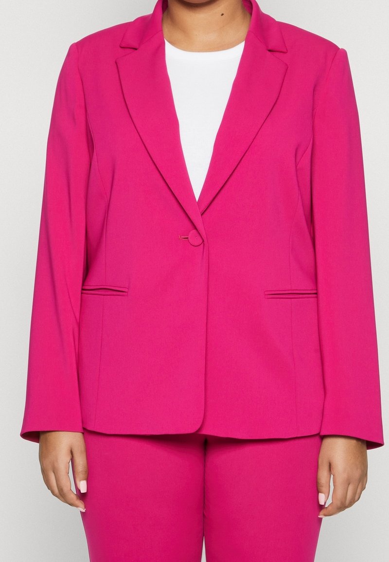 Klänning i klarröd färg med notchkrage, enkel knappstängning och framfickor. Snygg textur och skräddarsydd passform. Kombination med en vit överdel.