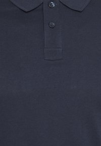 Polo in blu navy realizzato in tessuto testurizzato, caratterizzato da un colletto e tre bottoni frontali con bottoni scuri abbinati.