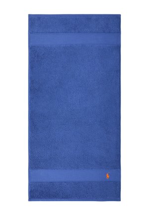 Serviette de bain rectangulaire bleue avec des bordures texturées et un petit logo brodé d'un joueur de polo orange près d'un coin.