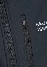 Black zippered jacket featuring textured fabric, side pocket with a smooth zipper, and white printed "HALO 1968" on the front.