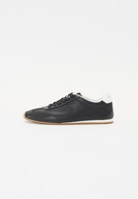 Musthave musta tennis jalaga tekstuuriga nahk, lipsud ees, valge pehme kaelus ning pruun kummist tald, millel on lokkis muster.