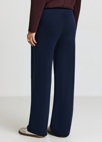 Pantalons larges en navy en tissu doux avec une taille élastique, présentant une texture lisse et sans motifs ni éléments visibles.