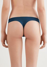 Granatowe majtki bikini wykonane z gładkiego, elastycznego materiału. Posiadają niską talię, minimalne zakrycie z tyłu oraz bezszwowy krój pasa.