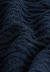 Marinblauer, strukturierter Stoff mit Wellenmuster, weich und plüschig, mit dicken Garnen und verschiedenen Blautönen, die Tiefe erzeugen.
