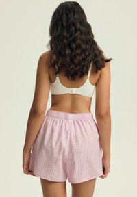 Bawełniane szorty piżamowe w różowym i białym wzorze w kratkę, z elastycznym pasem i luźnym krojem. Widok z tyłu.