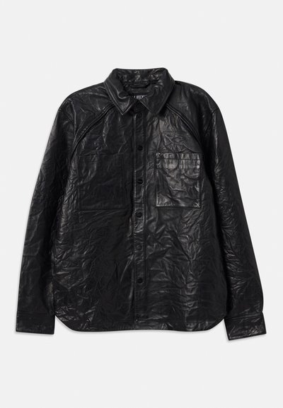 Μαύρο δερμάτινο πουκάμισο με ρυτιδωτή υφή, διαθέτοντας δύο τσέπες στο στήθος, κουμπί κλεισίματος και κλασικό γιακά. Μακριά μανίκια και χαλαρή εφαρμογή.