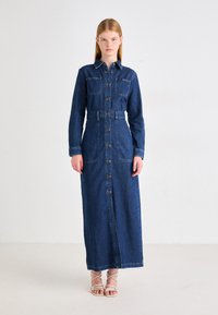 Vestido de camisa de mezclilla con mangas largas, cuello con solapa, cierre frontal de botones, dos bolsillos en el pecho, cintura ajustada y falda de longitud completa. Color índigo.