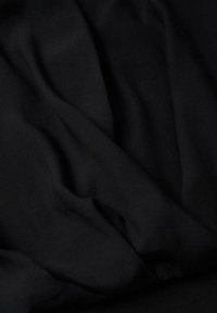 Tessuto nero con una consistenza liscia, caratterizzato da pieghe e rughe sottili, evidenziando la sua natura leggera e flessibile.