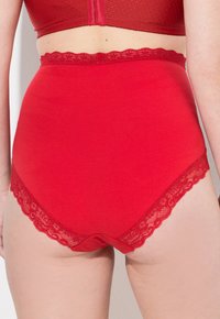 Rode hoge taille onderbroek van een gladde stof met een kanten rand langs de taille, wat zorgt voor een contrasterende textuur en ontwerpdetail.