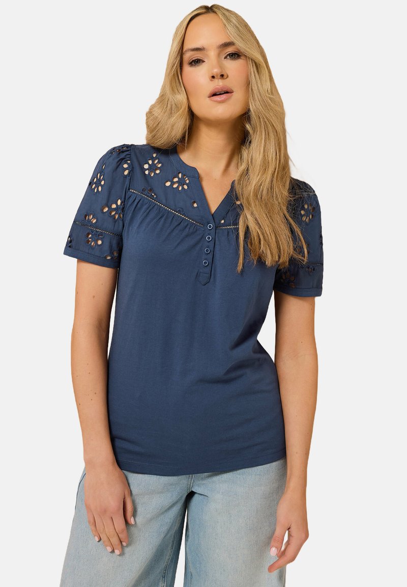 Marineblå bomulds T-shirt med korte pufærmer, øjenlidsblomsterbroderi, V-hals og tre-knaps placket foran.