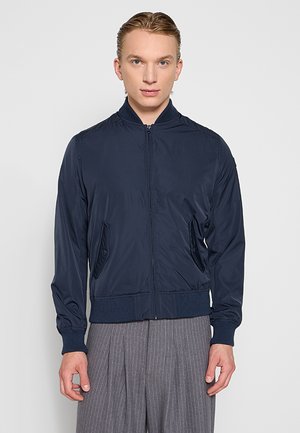 Marineblau Bomberjacke mit Reißverschluss, gerippten Bündchen und Saum, seitlichen Taschen und minimalen Nähdetails, aus glattem synthetischem Material gefertigt.
