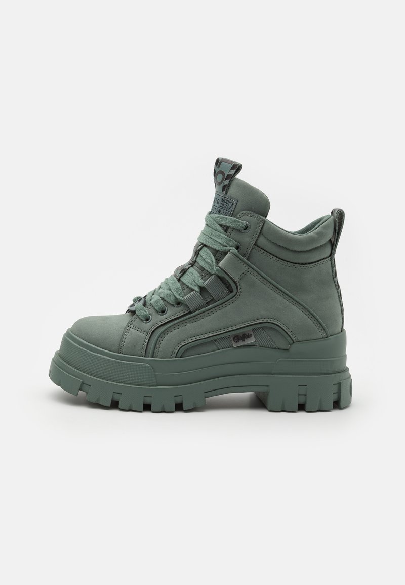 Roheline kõrge ümberpööratud sneaker, mis on valmistatud tekstuuritud materjalist. Sel on paks platvormitald, ümarad paelad ja tagumine aas mugavaks jalga panemiseks.