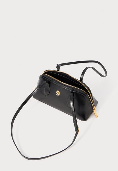 Bolsa de mão de couro preto com um design de dois zíperes, detalhes em metal dourado e uma alça de ombro destacável. Superfície suave e marcação mínima.