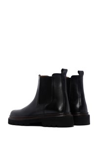 Zwarte leren Chelsea-boots met elastische zijpanelen, textuuraccent en een robuuste rubberen zool. Voorzien van trekhulpjes voor gemakkelijke aan- en uittrekken.