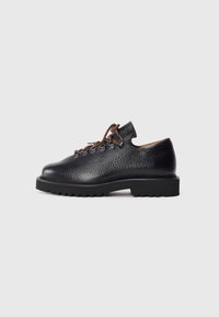 Black textured leather hiking-style shoe with thick lug sole and brown and black round laces threaded through metal eyelets.
