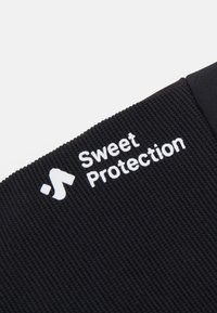 Melna auduma ar ribotu tekstūru, uz kura redzams baltais logo "Sweet Protection" un blakus esošs abstrakts simbols.