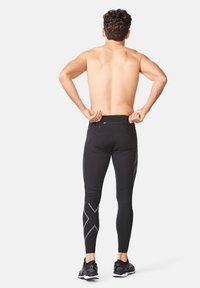 Sorte atletiske leggings med slim fit, der har et reflekterende geometrisk mønster på underbenet og en diskret baglomme.