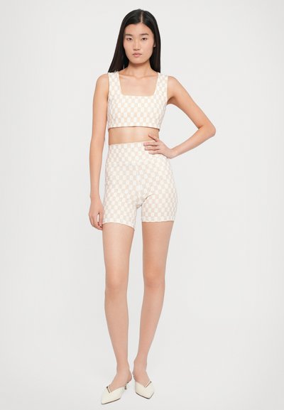 Tvådelsoutfit med en crop top och högmidjade shorts. Krämf�ärgad bas med ett geometriskt mönster i ljusbrunt. Slät tygtextur.
