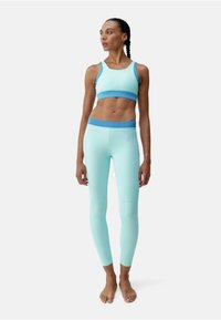 Set sportiv de culoare albastru deschis, compus dintr-un sutien cu bretelelate și colanți cu talie înaltă. Material neted și elastic cu accente contrastante.